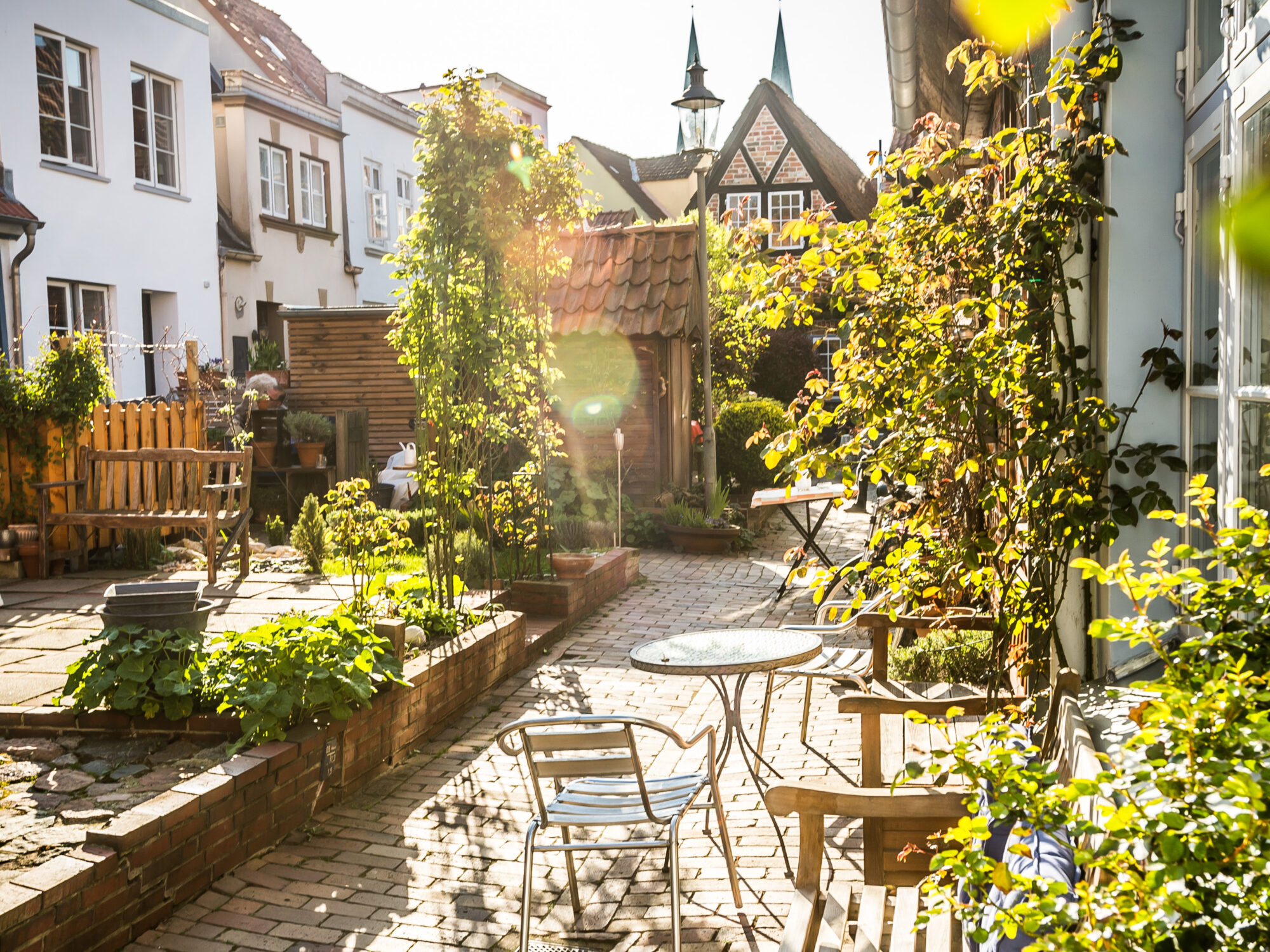 7 × Sommer in Lübeck erleben 17 Ein idyllischer Innenhof in Lübeck, bekannt als Rosengang, an einem sonnigen Tag.